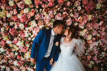 beautiful bride and groom on the background of a wall of flowers