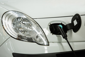 Electric car charged on a charging station by night. Close up.