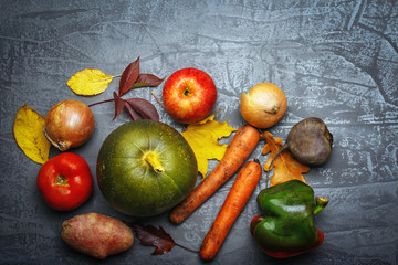 Creative image of vegetables on a .gray background. Pumpkin, potatoes, tomato, onions, carrots, peppers, apple.
