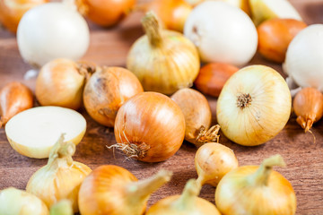 various fresh onions on a wooden table. wallpaper for grocery shopping and cooking food concept