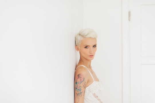 Woman with White Hair in White Clothes in a White Room with Watercolor Tattoo