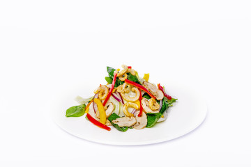 Pan-Asian salad, vegetables with fried squid rings. On a white plate on a white background