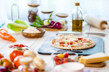 Fototapeta na wymiar raw fresh homemade traditional italian pizza with tomatoes, cheese and han on wooden cooking table with ingredients. wallpaper for pizzeria and food concept