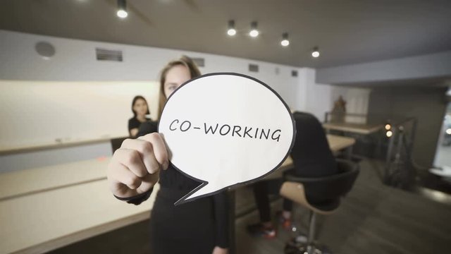 Girl shows the paper with word "Co-working"