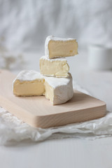 Sliced fresh camembert cheese on the white wooden table. Selective focus