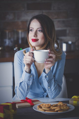Beautiful young woman sitting and at kitchen
