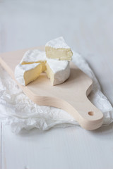 Fototapeta na wymiar Sliced fresh camembert cheese on the white wooden table. Selective focus