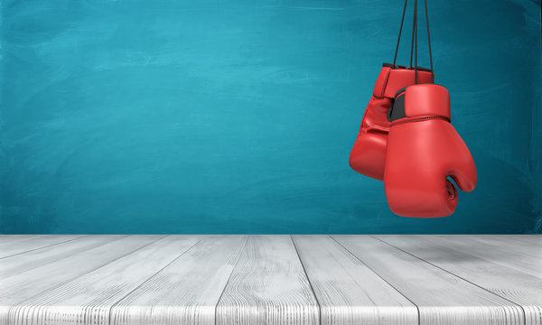 3d rendering of two red boxing gloves hanging above a wooden desk in front of a blue blackboard background.