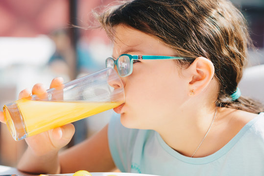 Portrait of a pretty child girl holding glass with tasty orange juice
