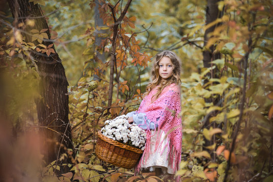 Little girl in the forest with a big basket of flowers.