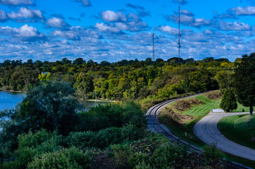 Single train track and parallel road curving into a forest