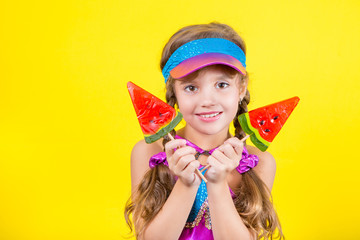 Beautiful little girl with large Lollipop. Studio portrait on a yellow background
