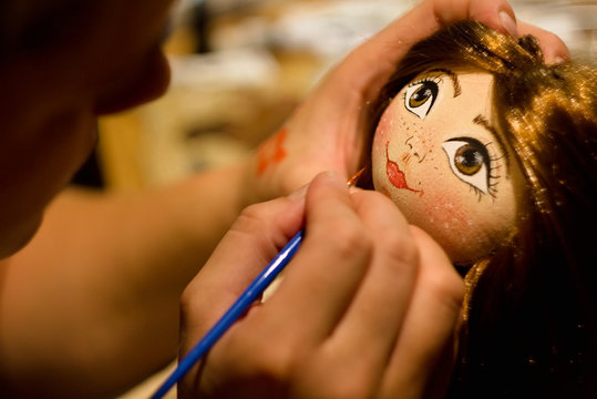 Painting face hand sewing home-made doll.