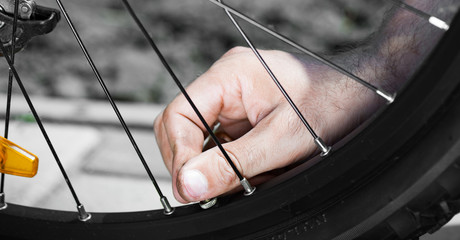 The panorama of side view of the man is pumping a bike wheel on the street.