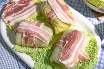 Zubereitung von Wirsingrouladen mit Speck auf Kohlblättern