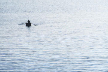 Old fisherman on rowing boat at dawn