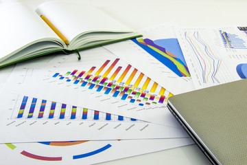 Preparing report. Blue graphs and charts. Business reports and pile of documents on gray reflection background.