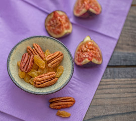 Pecan and dried fruit composition on a lilac tablecloth on a wooden table.
