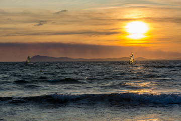 Fototapeta na wymiar Sunset over the sea or ocean and extreme freestyle sport windsurfing