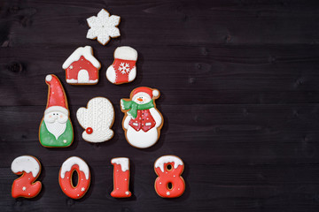Top view of christmas tree made from gingerbread cookies on wooden background, copy space. New Year 2018 postcard with gingerbread snowman, santa, snowflake, house, mitten, christmas sock