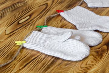 Fototapeta na wymiar Set of cute knitted cashmere newborn baby socks and gauntlets hanged on pins against wooden background