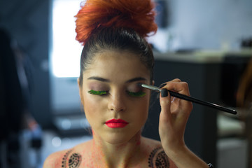 Obraz premium stylist making fluorescent glowing Body Art make-up to sexy fashion model .