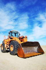 Orange loader bulldozer with cloud sky