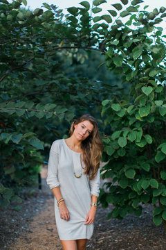 Beautiful woman in a sweater dress standing outside by a tree
