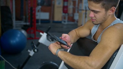 man uses fitness tracker and synchronization with mobile phone in the gym
