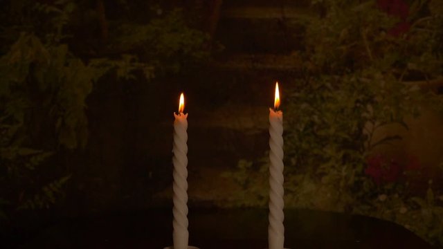 Slow motion. Two candles rotate by circle. Light of the fire of two candles. Concept for meditation or xmas holiday. Garden background dark low key.