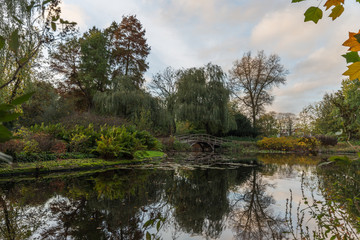 Autumn leaves color a gardens with lake and bridge