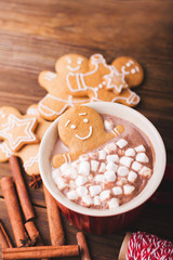 Gingerbread man bathes in a cup of hot chocolate or cocoa with marshmallow. Gingerbread Man in red cup