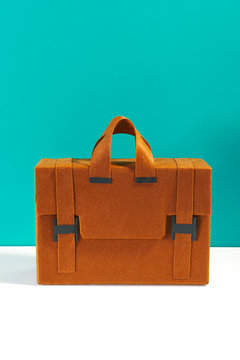 Diy briefcase made by cardboard and felt in front a blue background.