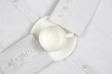 empty white coffee Cup and saucer on a white shirt.