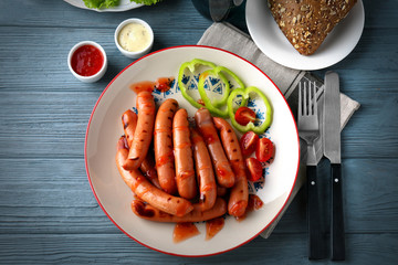 Plate with delicious grilled sausages on color wooden background