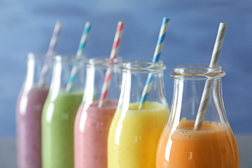 Bottles with yummy smoothie against color background