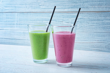 Glasses with yummy smoothie on light wooden background