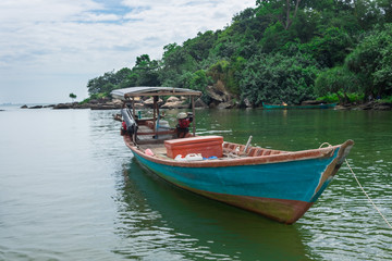 handmade, wooden fishing boat in the blue and green waters of Cambodia