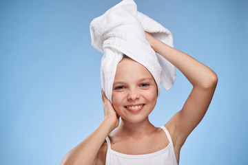 little girl in a white towel on her head smiling on a blue background