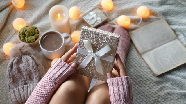Woman In Sweater And Socks Holding Gift Box For Christmas At Home. Closeup. 4K. 