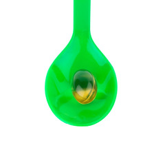 green plastic spoon..Capsules fish oil isolate on white background