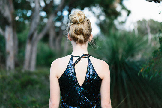 Back view of young woman wearing a sequinned party dress in the bush