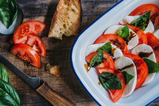 Freshly Made Caprese Salad With Mozzarella Cheese, Tomatoes And Basil in White Enameled Bowl