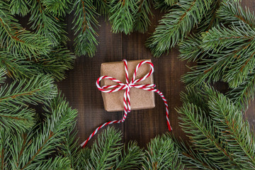Christmas fir tree branches and brown gift box  on dark rustic wooden background