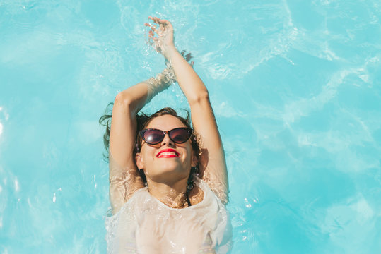 Pretty girl with retro sunglasses relaxing in the pool