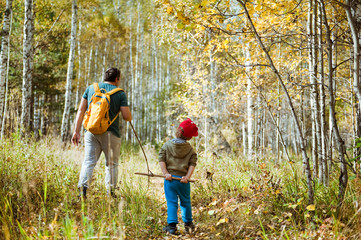 Father and son walking in autumn forest.