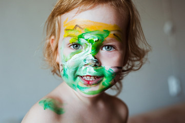 Child with green makeup on his face.