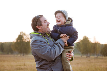 Dad plays with his son in autumn forest.