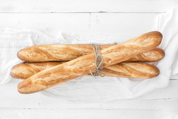 Freshly baked French baguettes on white wooden table. Top view