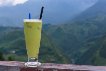 Glass of green drink with mountain landscape on the background